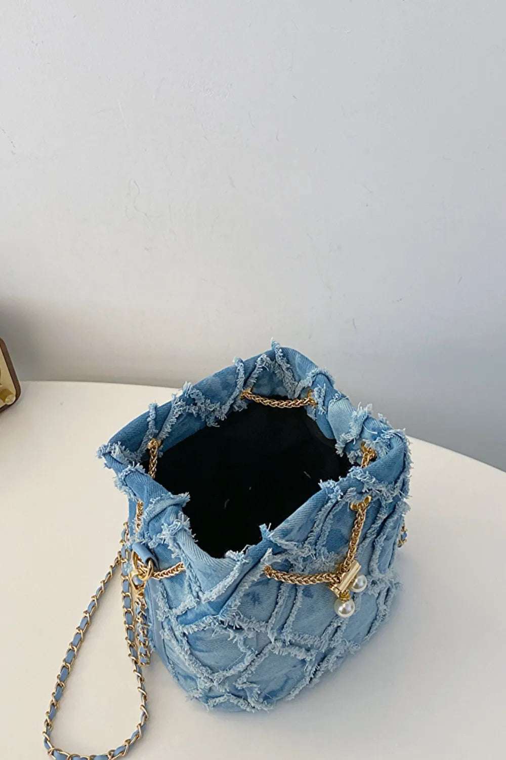 Chain Drawstring Raw Edge Denim Bucket Bag - Premium Crossbody Bag from Trendsi - Just $34.99! Shop now at Handbags Specialist Headquarter